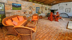 Un intérieur rustique avec des murs en pierre, des meubles en osier et une cheminée en pierre.