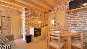 A cozy kitchen with wooden beams, brick walls, and a dining area with a table set for four. - Seaside Retreat in Marina di Grosseto (Starigrad)
