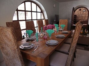 A dining table set with plates, glasses, and cutlery, surrounded by upholstered chairs. - Villa on an Exclusive Location in Dubrovnik With Pool (Dubrovnik)