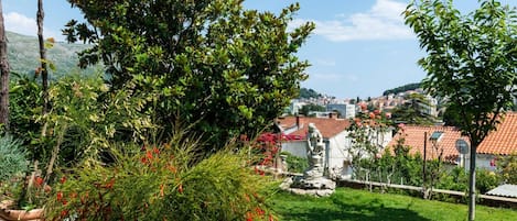 A residential area with a view of a town, a grassy lawn, and a statue.