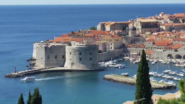 A coastal cityscape with historic architecture, a fortified castle, and a marina with boats. - Dubrovnik Apartment With Private Terrace (Dubrovnik)