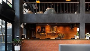 A modern interior with a reception desk, seating area, and exposed brick walls. - BED STATION HOSTEL KHAOSAN (Bangkok)