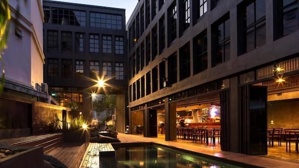 A modern building with a pool area, outdoor seating, and a bar. - BED STATION HOSTEL KHAOSAN (Bangkok)