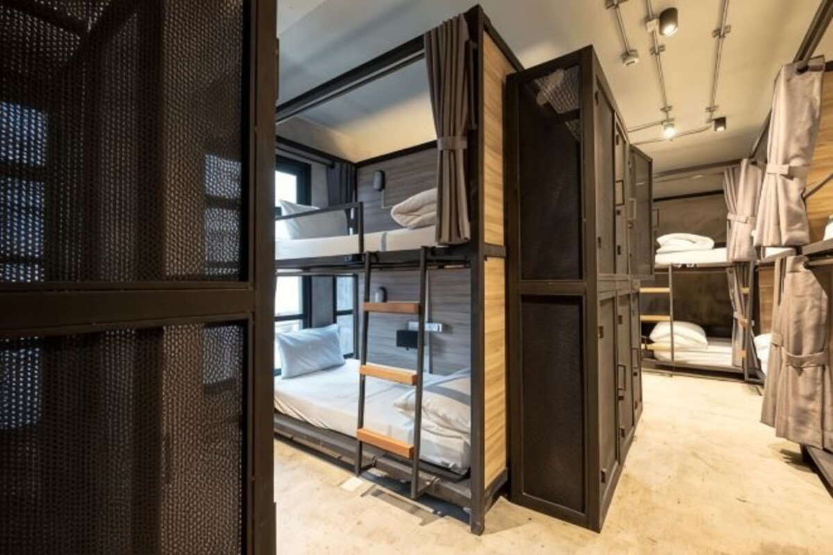A room with bunk beds, a large window, and a wardrobe.