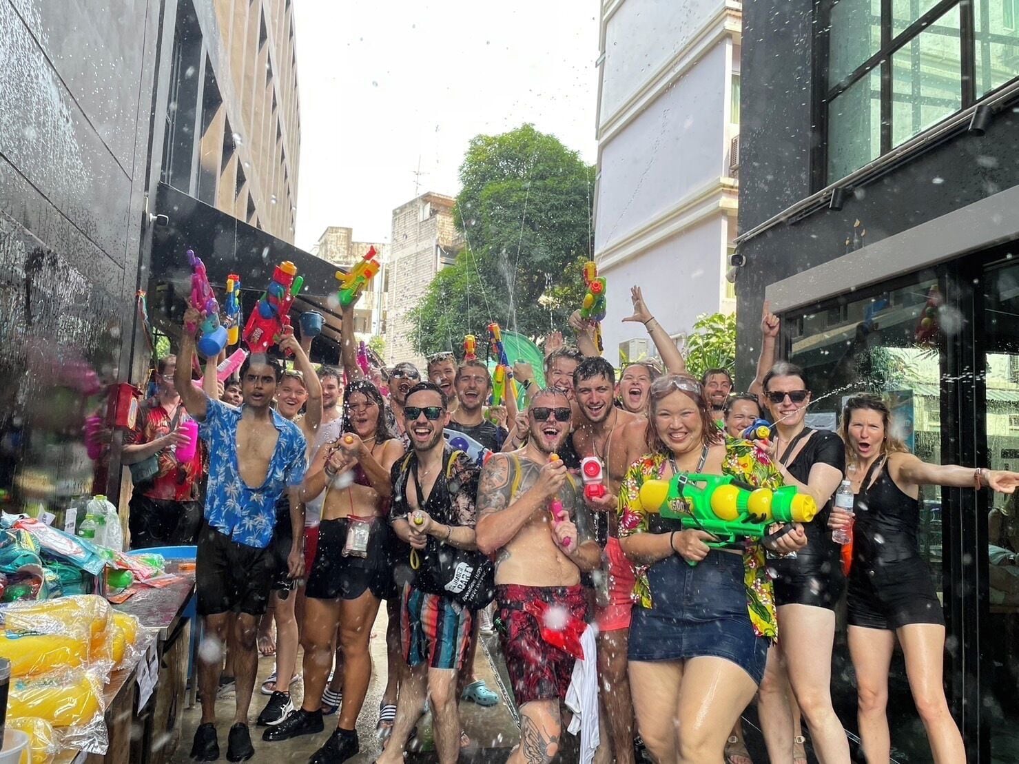 A group of people celebrating with water guns in an urban setting.