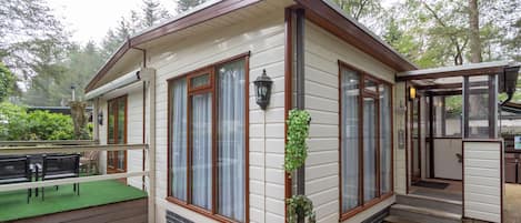 Een laag gebouw met een overdekte veranda, grote ramen en een klein terras.