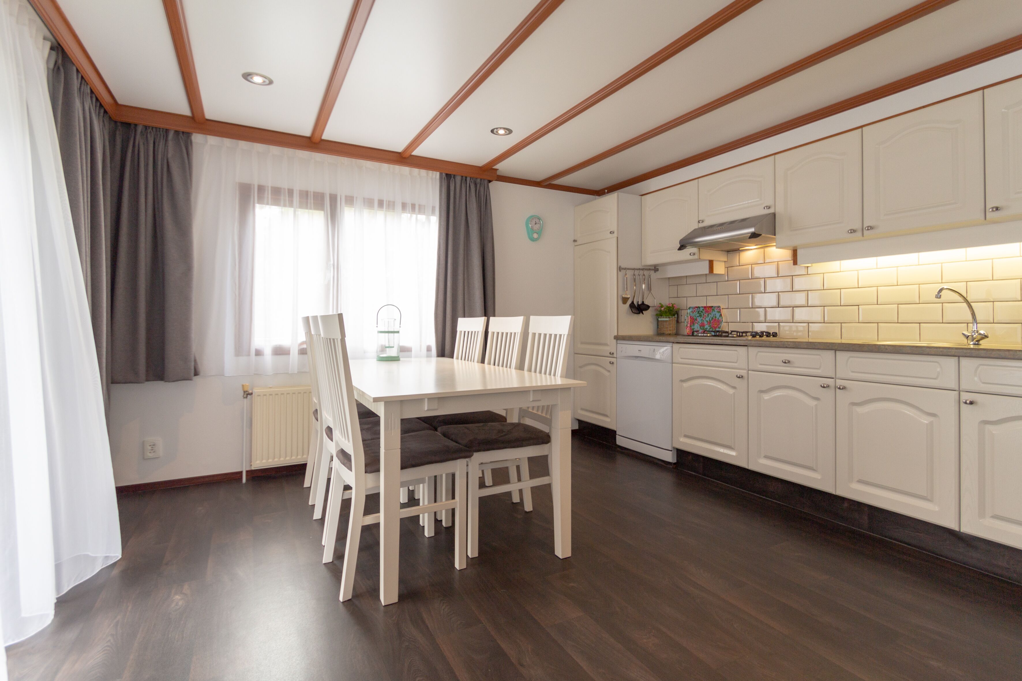 A modern kitchen with white cabinets, a wooden countertop, and a built-in dishwasher.