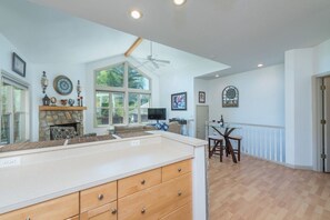 A spacious kitchen with a stone fireplace, wooden cabinets, and a dining area with a glass table and chairs.