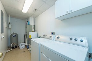 A laundry room with a front-loading washer and dryer, a water heater, and a utility sink.