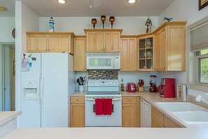 A kitchen with wooden cabinets, a white refrigerator, a microwave, a stove, and a red towel hanging on the oven handle.