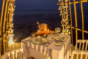 A table set for two with a view of the ocean, decorated with candles and flowers. - Mambruk Hotel & Convention (Anyer)