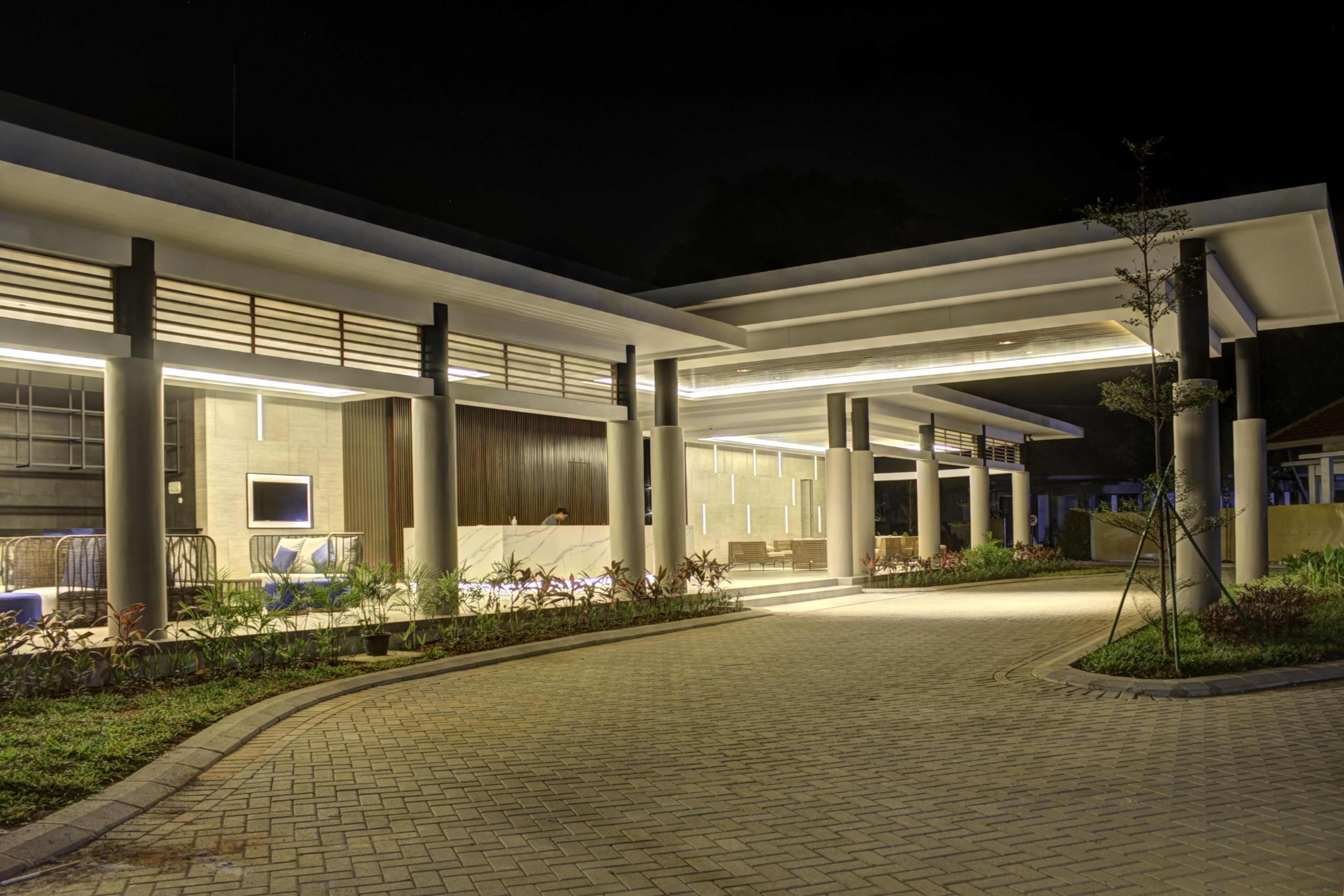 A modern building with a covered walkway, columns, and outdoor seating areas.