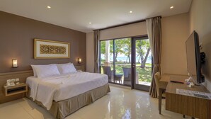 A hotel room with a large bed, a desk, a TV, and a view of the beach. - Mambruk Hotel & Convention (Anyer)