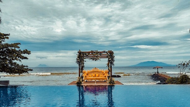 A pool with a wooden structure and a sofa in the center, surrounded by a beach and ocean view. - Mambruk Hotel & Convention (Anyer)