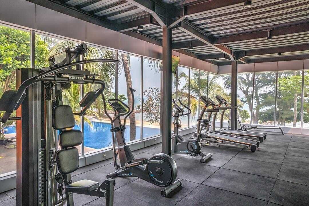 Une salle de sport équipée de machines de cardio, de machines de musculation et offrant une vue sur une piscine.