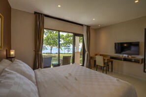 A hotel room with a large bed, a desk, a TV, and a view of the sea. - Mambruk Hotel & Convention (Anyer)