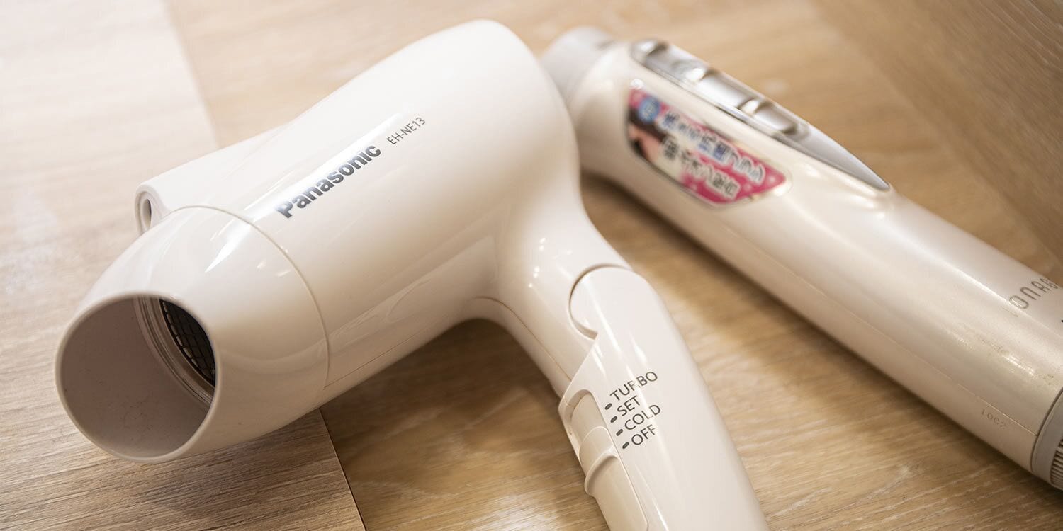 Un secador Panasonic y una botella de producto para el cabello sobre una superficie de madera.