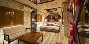 A hotel room with a large bed, a sofa, a wooden coffee table, and a mirror. - Hotel Jardin de Fleurs - Adult Only (Kyoto)