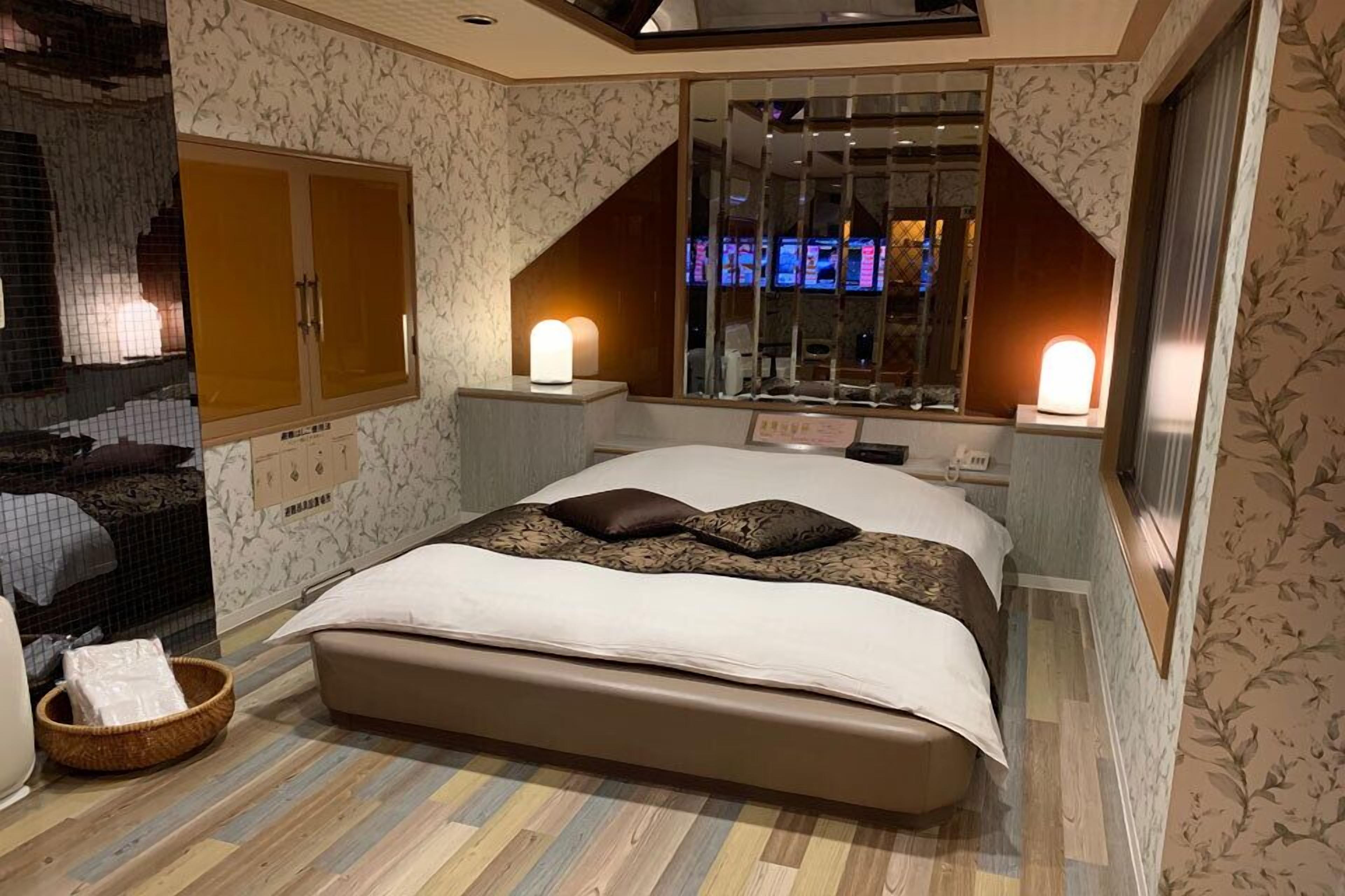 A bedroom with a large bed, two bedside lamps, a window with a view, and a decorative mirror.