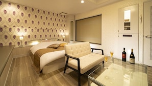 A hotel room with a bed, a sofa, a glass table, and two bottles of wine. - Hotel Jardin de Fleurs - Adult Only (Kyoto)