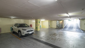 A parking garage with a white car parked in a spot. - Hotel Jardin de Fleurs - Adult Only (Kyoto)