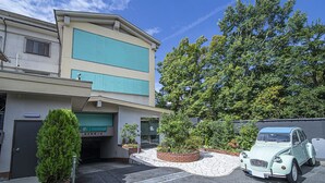 A building with a parking area and a vintage car parked in front. - Hotel Jardin de Fleurs - Adult Only (Kyoto)