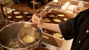 A person preparing food, specifically noodles, in a kitchen setting.