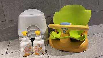 A baby changing station with a yellow and green seat, two baby soap dispensers, and a grey soap dispenser.