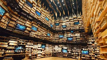 Uma estante grande e de vários níveis, repleta de livros, com várias telas exibindo conteúdo.