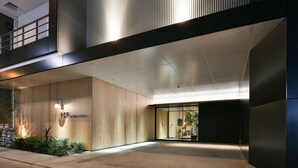 A modern hotel entrance with a wooden facade, a glass door entrance, and a well-lit interior. - REF Omiya by VESSEL HOTELS (Saitama)