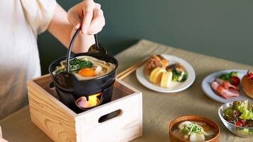 A wooden table with a pot of soup, a plate of food, and a bowl of salad.
