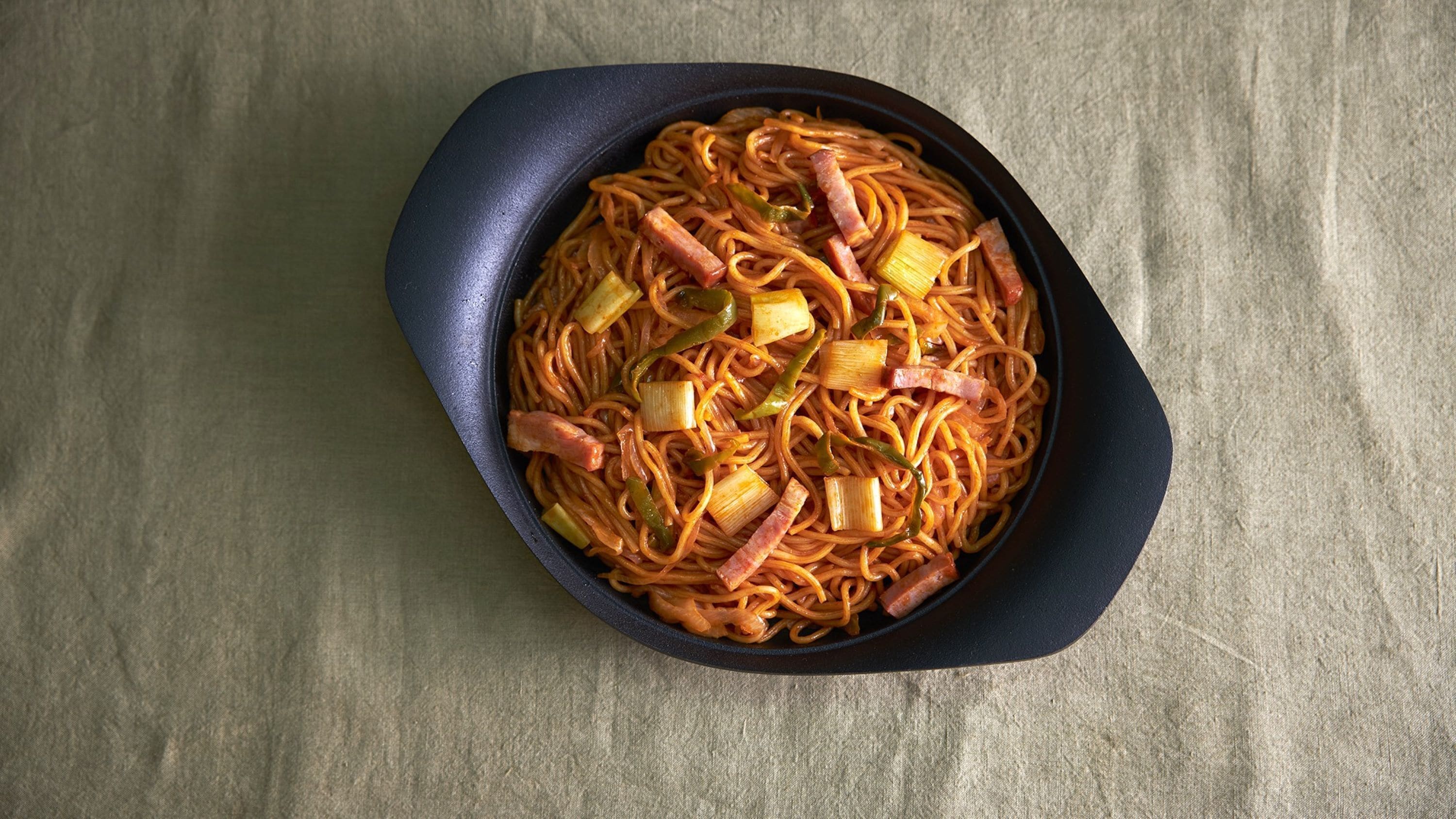 A bowl of noodles with vegetables and meat.