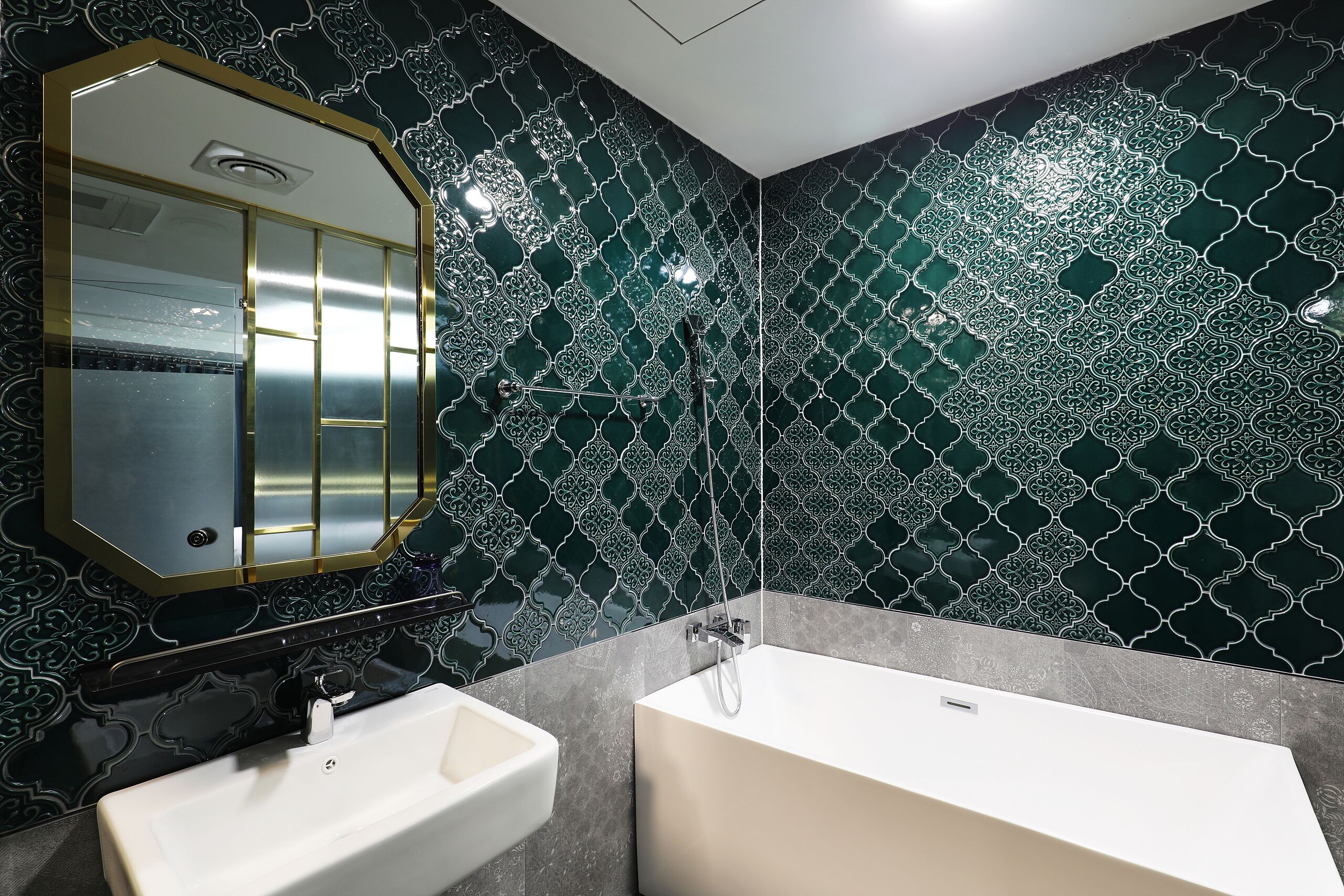 Un baño con lavamanos blanco, bañera y espejo con marco dorado.