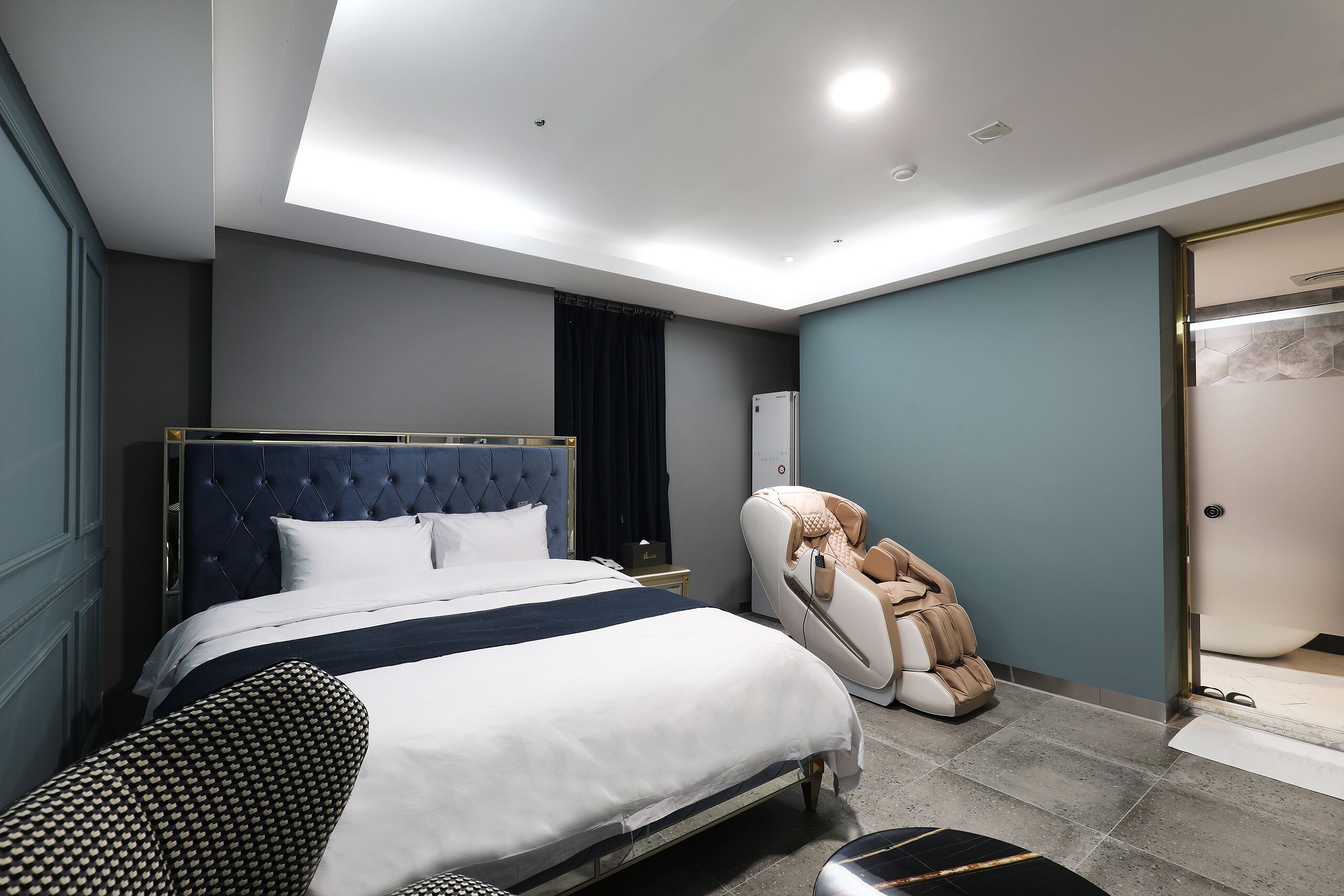 Un dormitorio moderno con una cama grande, una silla de masaje y un vestidor.