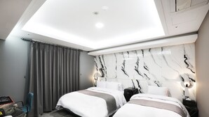 Et moderne hotelværelse med to senge, et skrivebord og en loftslampe.