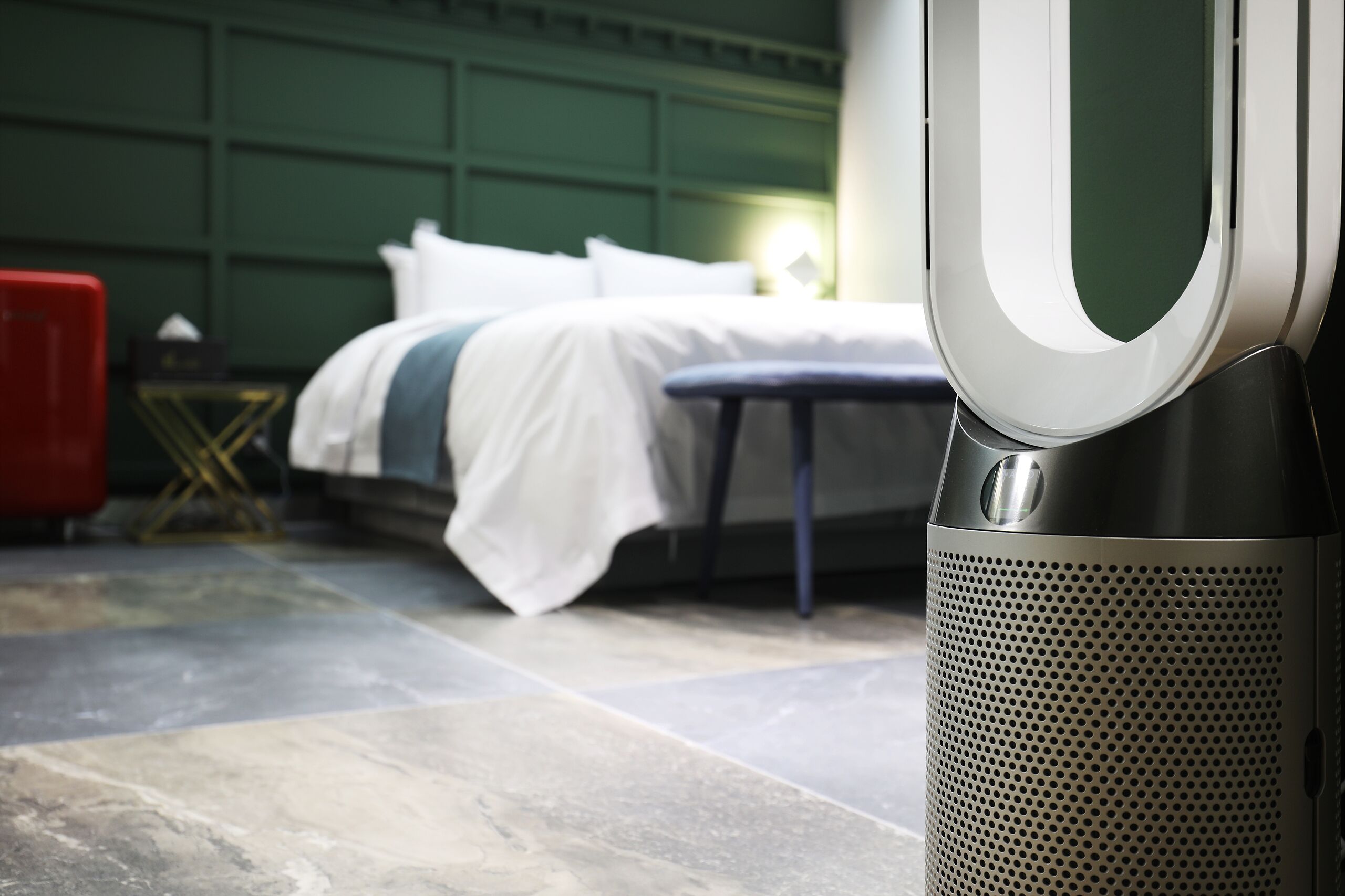 A modern hotel room with a neatly made bed, a bedside table, and a large speaker.