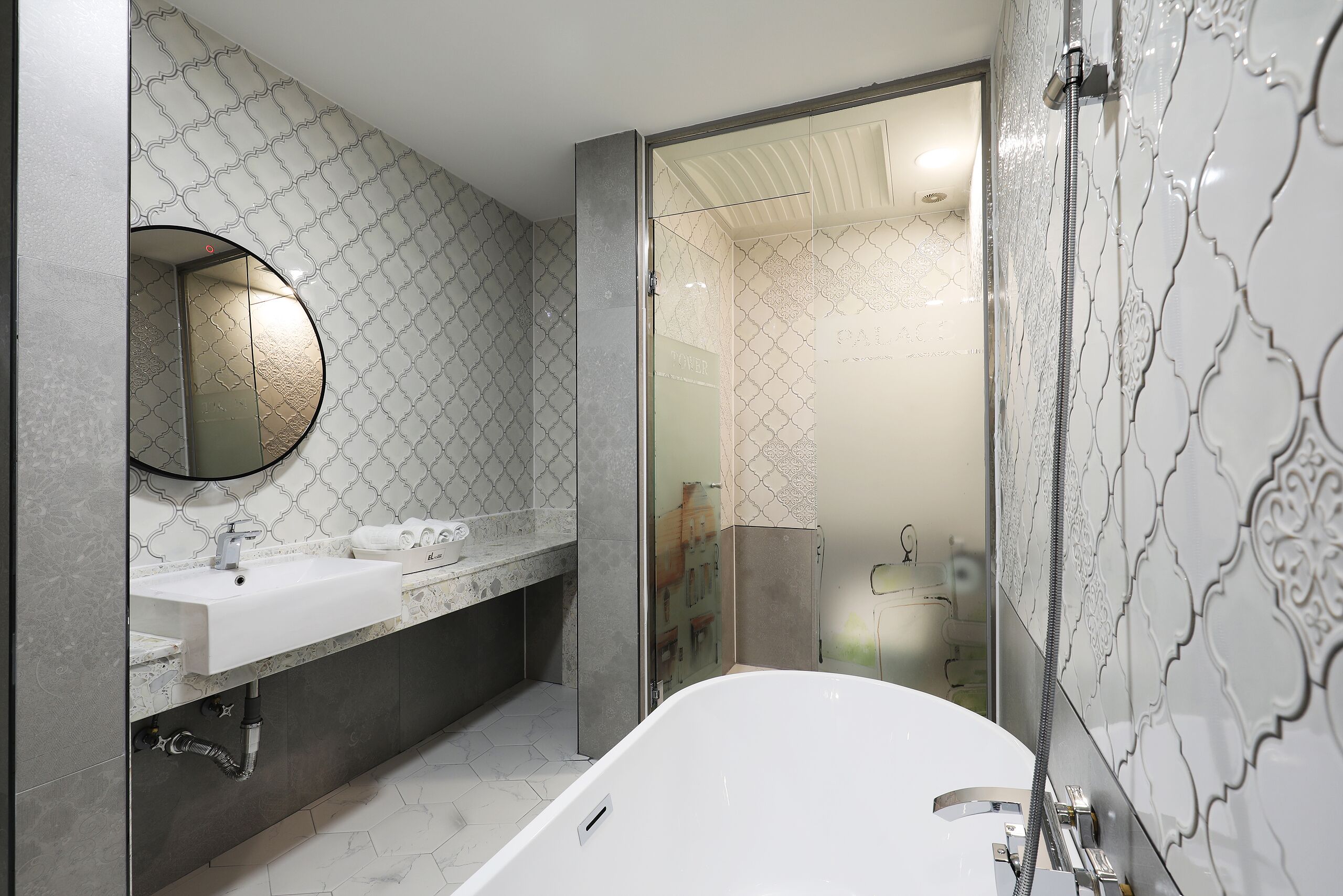 Ein modernes Badezimmer mit einem weißen Waschbecken, einem runden Spiegel und einer Badewanne.