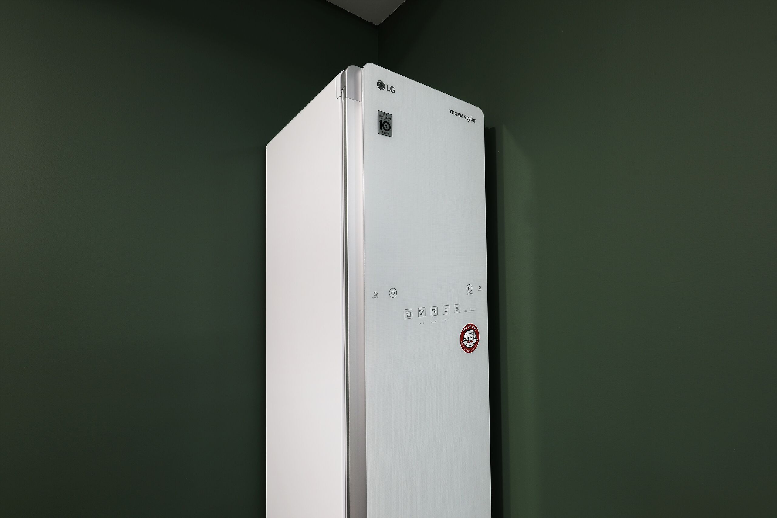 A white LG TOWER STYLE refrigerator with a control panel, set against a dark green wall.