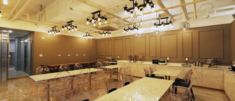 A modern restaurant with clear plastic chairs, marble tables, and pendant lighting.