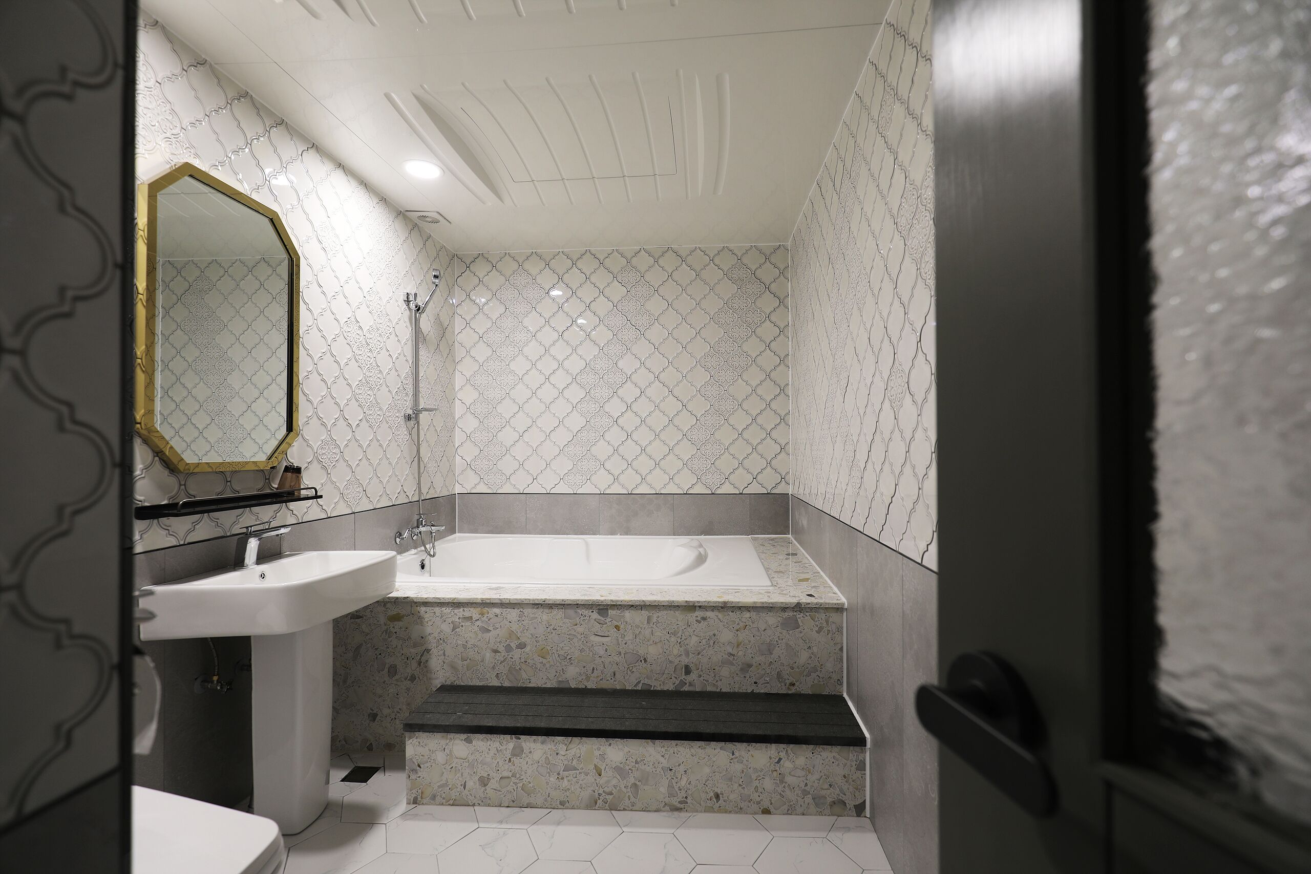 A modern bathroom with a freestanding bathtub, a pedestal sink, and a large mirror.