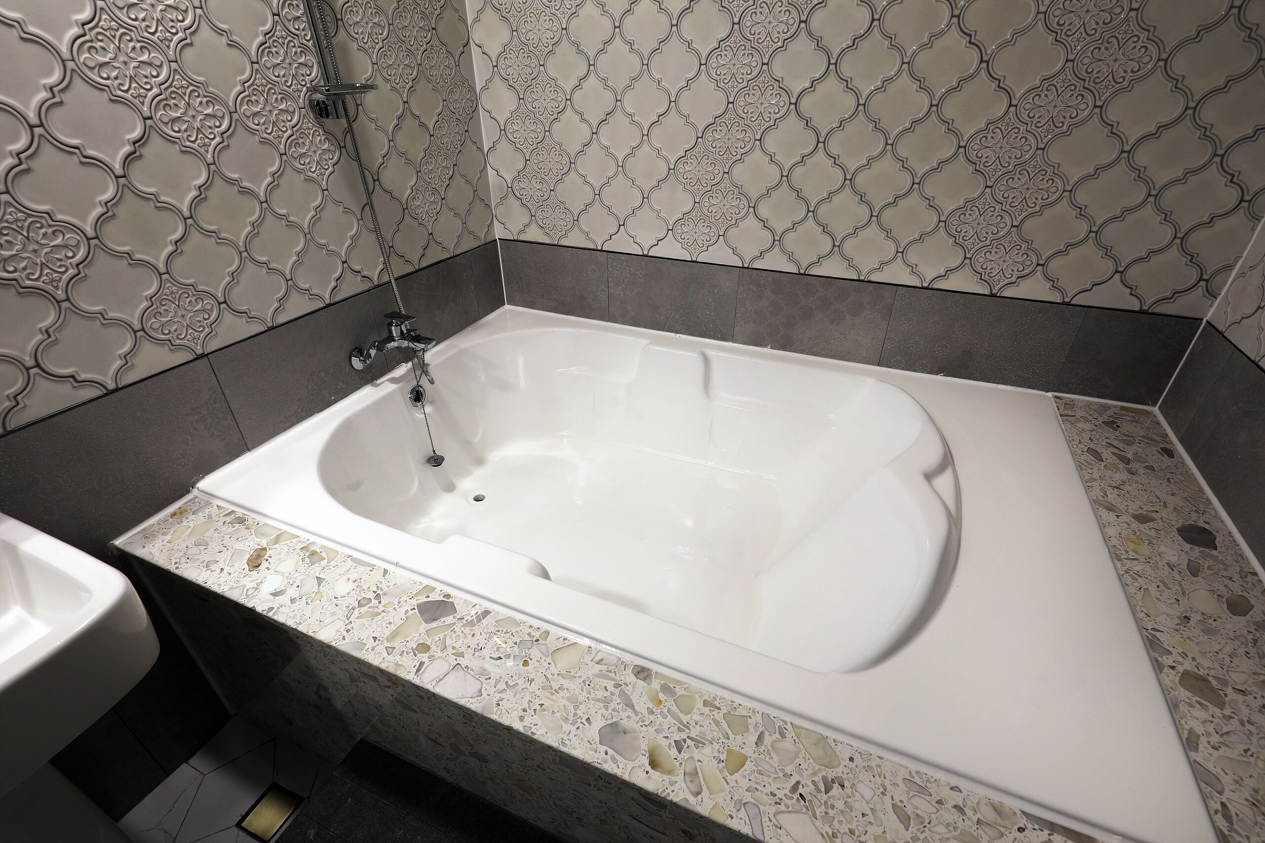 A modern bathroom with a freestanding bathtub, a sink, and patterned tiles.
