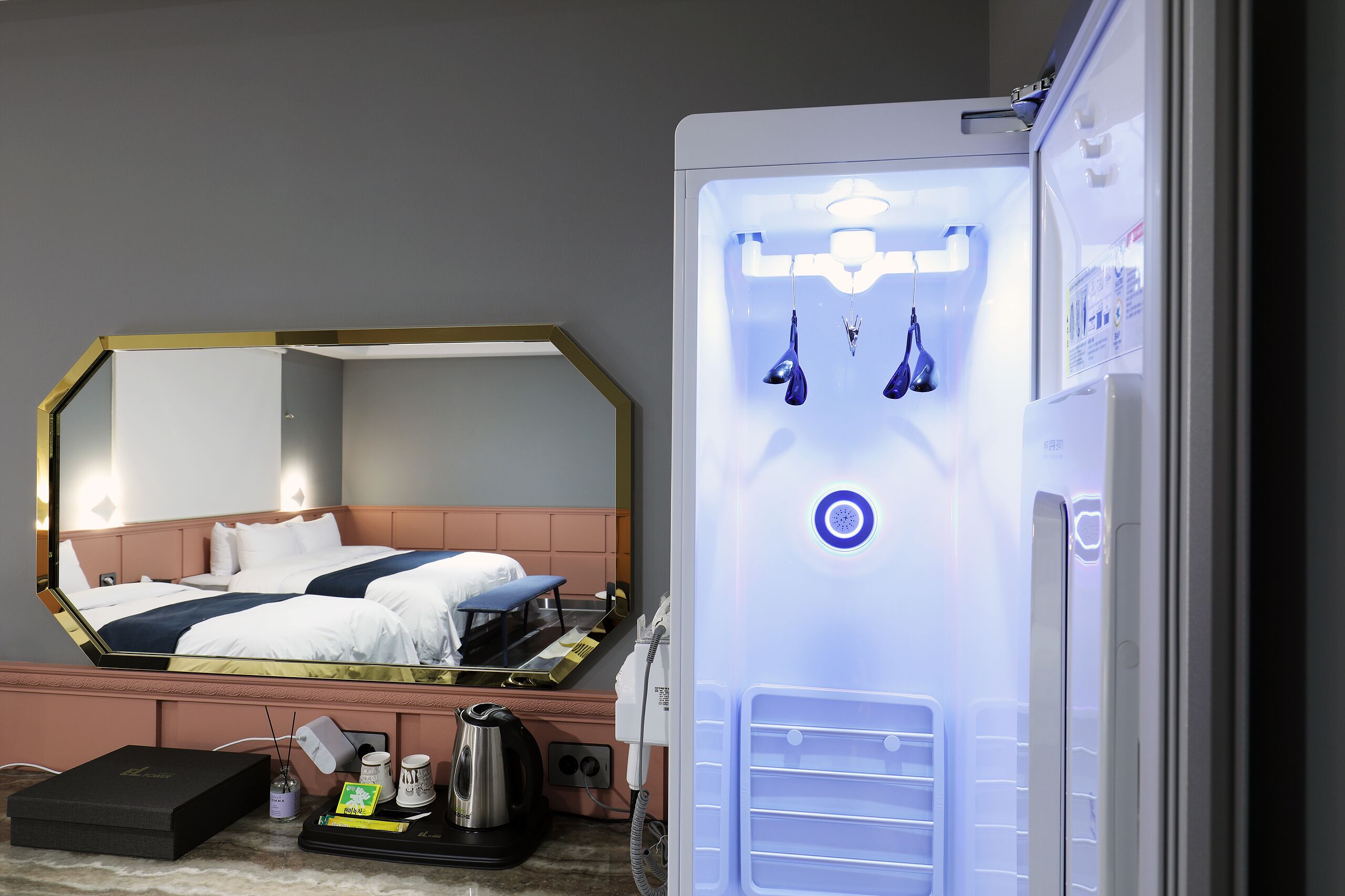 Una habitación de hotel con cama, un minibar, un espejo y un refrigerador.