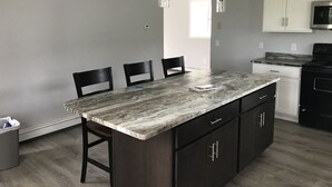 A modern kitchen with dark cabinetry, a marble countertop, and pendant lighting. - Simple and clean living by the beach! (Narragansett)