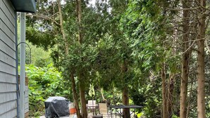 A backyard with a patio, outdoor furniture, potted plants, and a garden area. - Simple and clean living by the beach! (Narragansett)