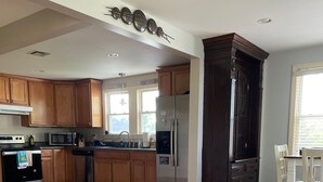 Un'ampia cucina con mobili in legno, elettrodomestici in acciaio inossidabile e un'area pranzo con tavolo e sedie.