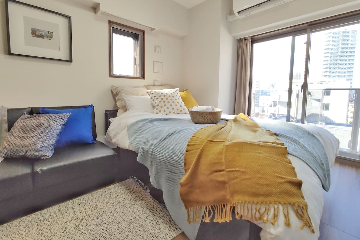 A modern bedroom with a bed, a window, and an air conditioning unit.