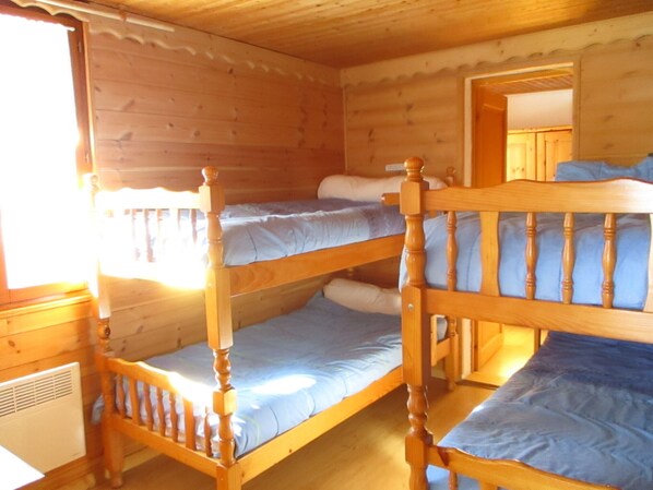 A cabin with three bunk beds, wooden walls, and a window.