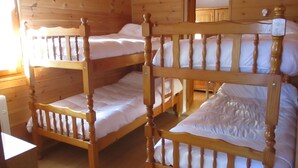 A bunk bed room with wooden walls and a wooden headboard.