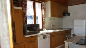 A compact kitchen with wooden cabinets, a microwave, a dishwasher, and a refrigerator.