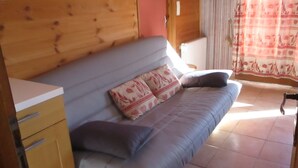 A wooden interior with a grey sofa, two pillows, and a wooden cabinet.